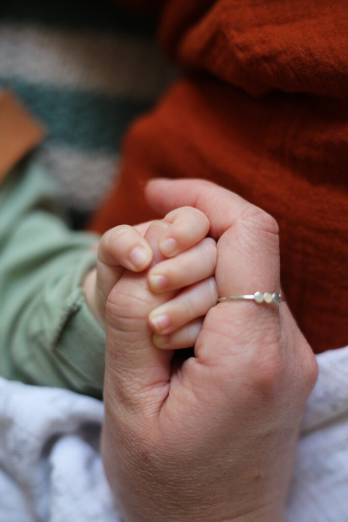 Frau hält Hand eines Babys - Bild im Beitrag zu Alina Esken